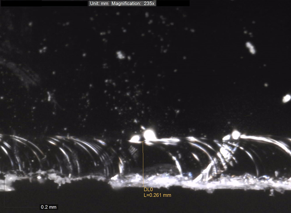 Microscopic evaluation of cut edge hackle formation in 1.6 mm glass before pre-processing development.
